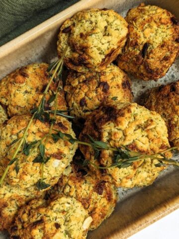 A serving dish with a pile of air fried stuffing balls topped with fresh herbs.