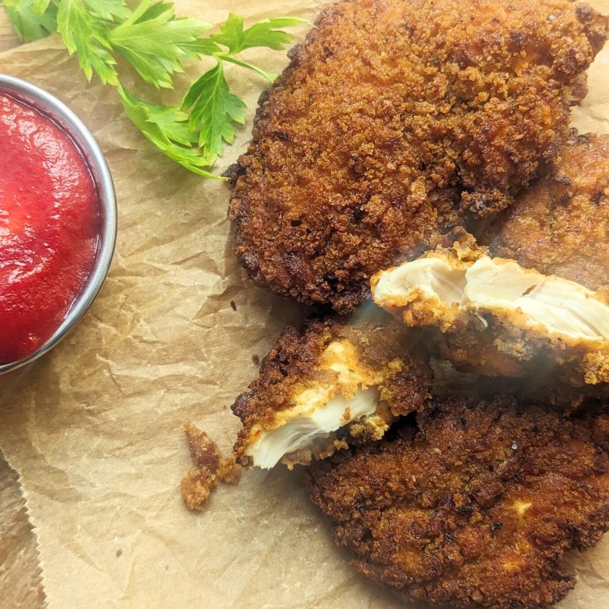Chicken tenders on a serving board with ketchup at the side.