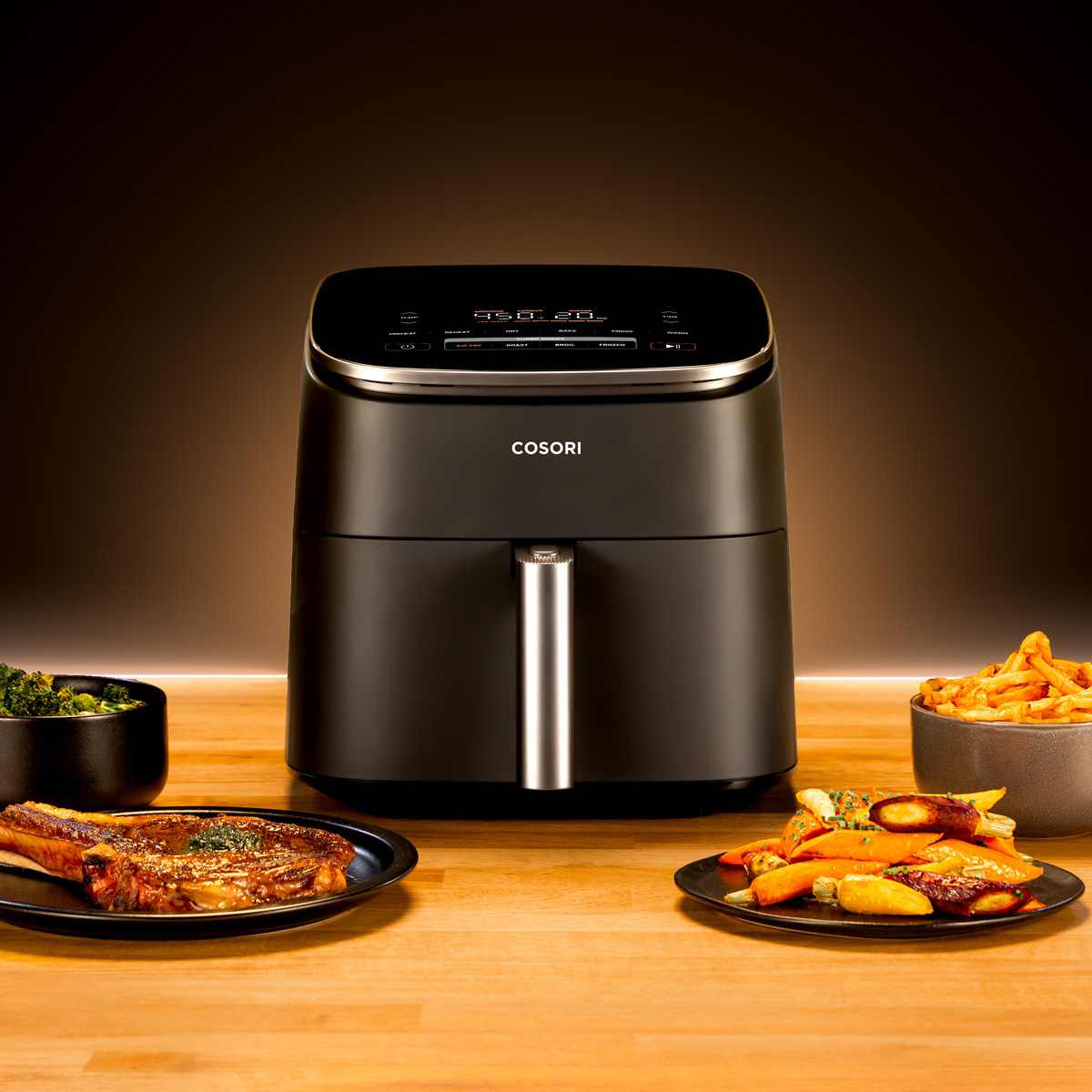 Cosori TurboBlaze air fryer on a kitchen worktop with plates of food alongside it.