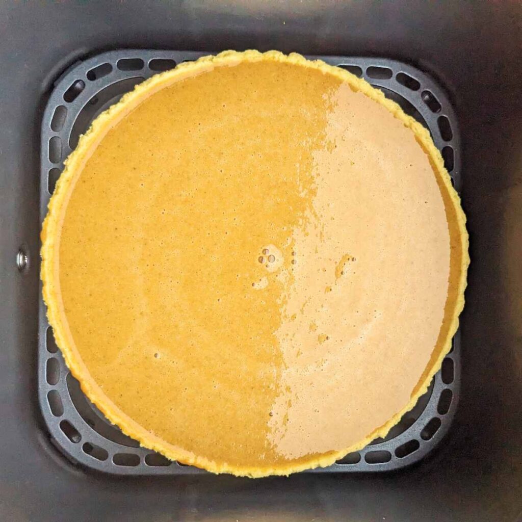 A pastry case filled with pumpkin pie mixture in a Cosori air fryer basket.