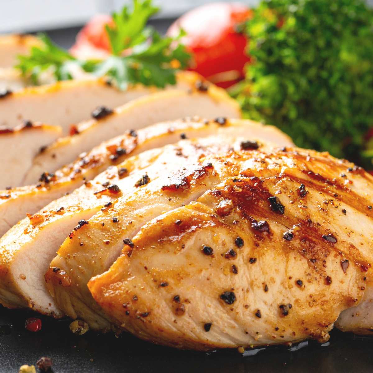 Sliced chicken breast on a plate with salad at the side.