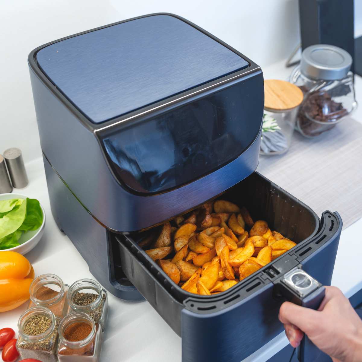 An air fryer with the drawer pulled out to show the cooked chips inside.
